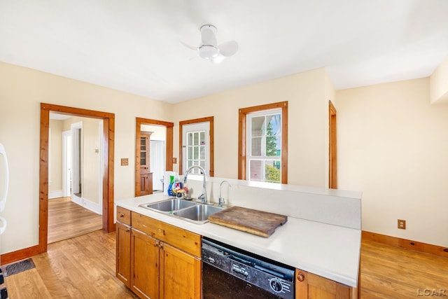 kitchen featuring light wood-type flooring, ceiling fan, sink, dishwasher, and an island with sink