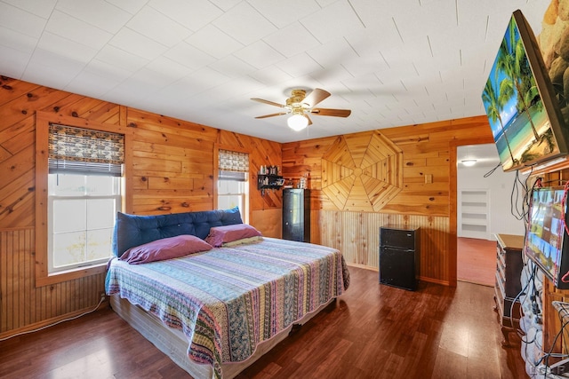 bedroom featuring multiple windows, wood walls, dark hardwood / wood-style flooring, and ceiling fan