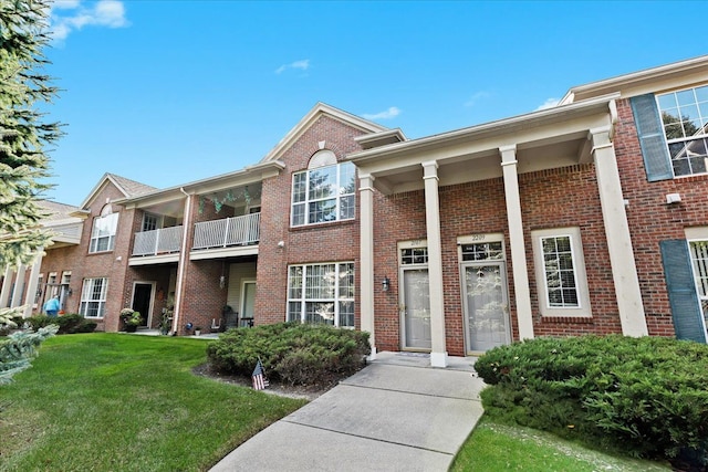 view of front of house featuring a balcony and a front yard