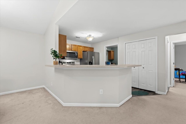 kitchen with light colored carpet, kitchen peninsula, and stainless steel appliances