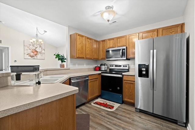 kitchen featuring appliances with stainless steel finishes, pendant lighting, a chandelier, dark hardwood / wood-style floors, and lofted ceiling