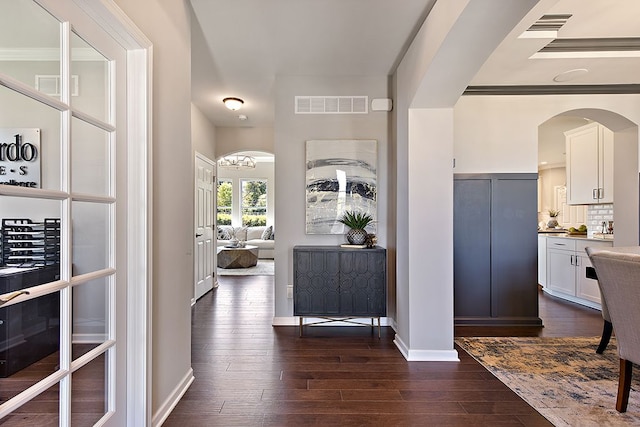 hallway featuring french doors, an inviting chandelier, dark wood-type flooring, and crown molding