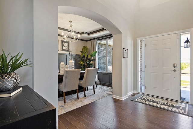 foyer entrance featuring ornamental molding, dark hardwood / wood-style flooring, a raised ceiling, and a notable chandelier