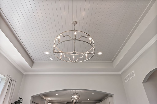 interior details with a raised ceiling, crown molding, and an inviting chandelier