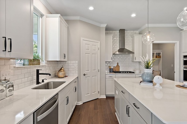 kitchen featuring white cabinets, wall chimney exhaust hood, dark hardwood / wood-style floors, appliances with stainless steel finishes, and decorative light fixtures