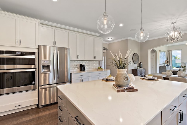 kitchen featuring light stone countertops, white cabinetry, stainless steel appliances, dark hardwood / wood-style floors, and pendant lighting