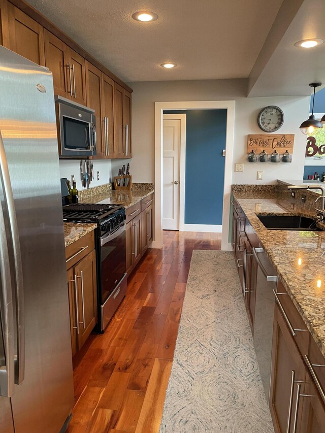 23739 Grandview Ct, Sturgis, MI 49091 - kitchen featuring stainless steel appliances, a sink, brown cabinetry, dark wood-type flooring, and light stone countertops