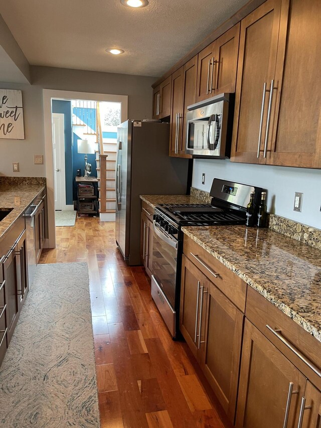 23739 Grandview Ct, Sturgis, MI 49091 - kitchen with stainless steel appliances, brown cabinetry, light wood-style flooring, stone countertops, and recessed lighting