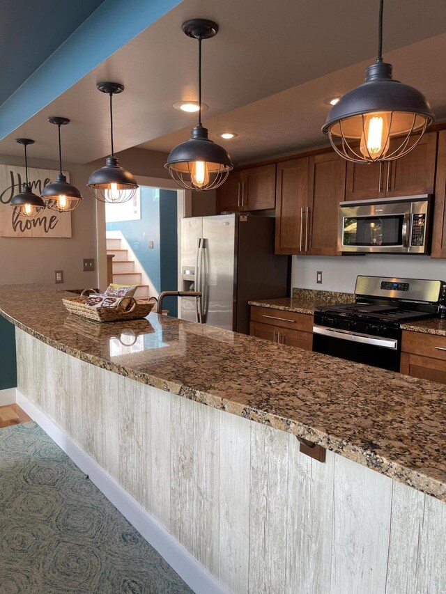 23739 Grandview Ct, Sturgis, MI 49091 - kitchen with stainless steel appliances, dark stone counters, baseboards, brown cabinets, and pendant lighting