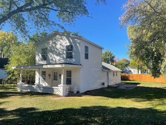 back of property featuring a yard and covered porch