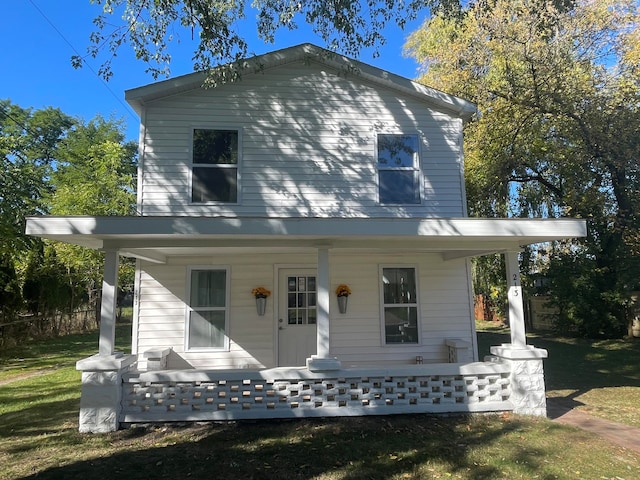 back of house featuring covered porch and a lawn