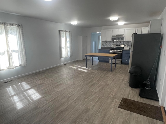 kitchen with white cabinets, decorative backsplash, a healthy amount of sunlight, and stainless steel range oven