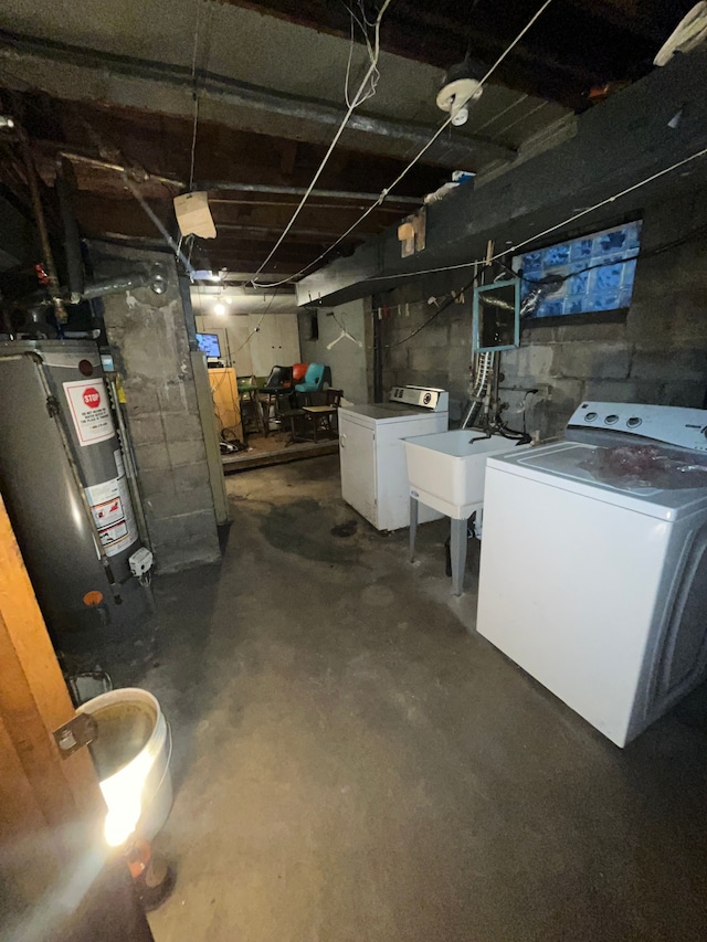 basement with washing machine and clothes dryer, sink, and water heater