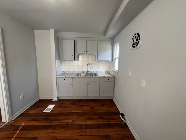 kitchen featuring decorative backsplash, light stone countertops, sink, and dark wood-type flooring