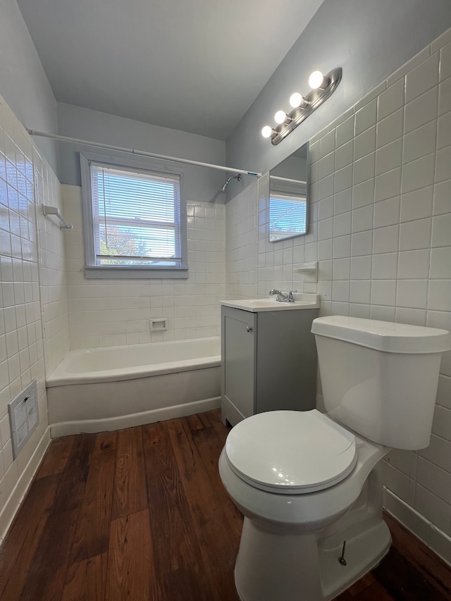 full bathroom featuring wood-type flooring, vanity, tiled shower / bath combo, and tile walls