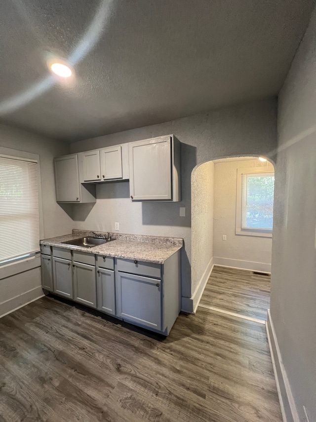 kitchen with gray cabinetry, dark hardwood / wood-style floors, sink, and a textured ceiling