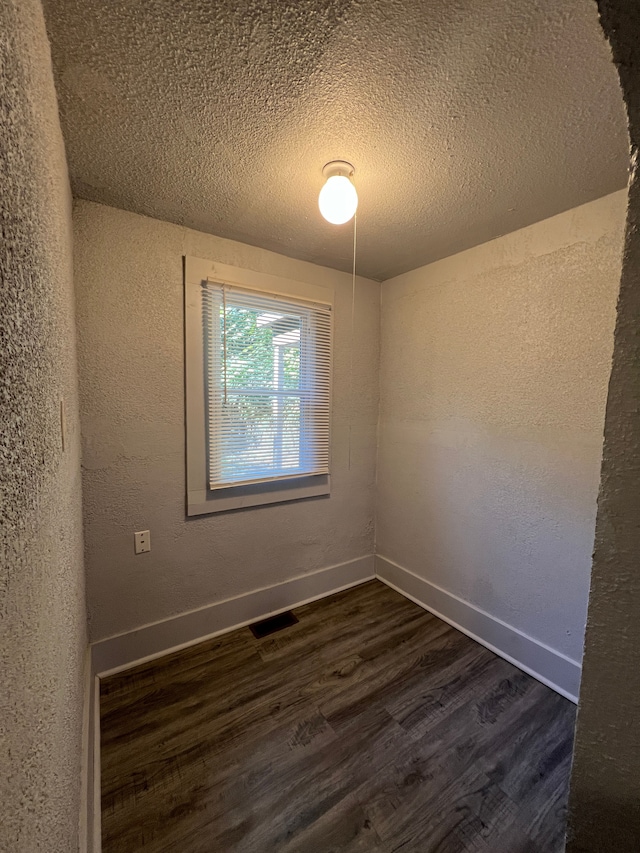 empty room featuring dark hardwood / wood-style floors and a textured ceiling