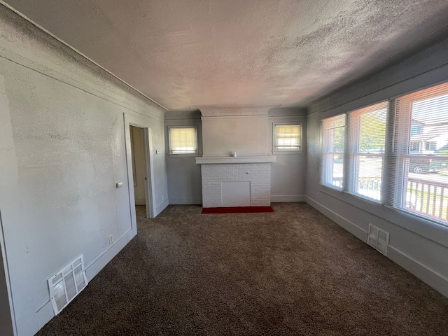 carpeted spare room featuring a textured ceiling and a brick fireplace