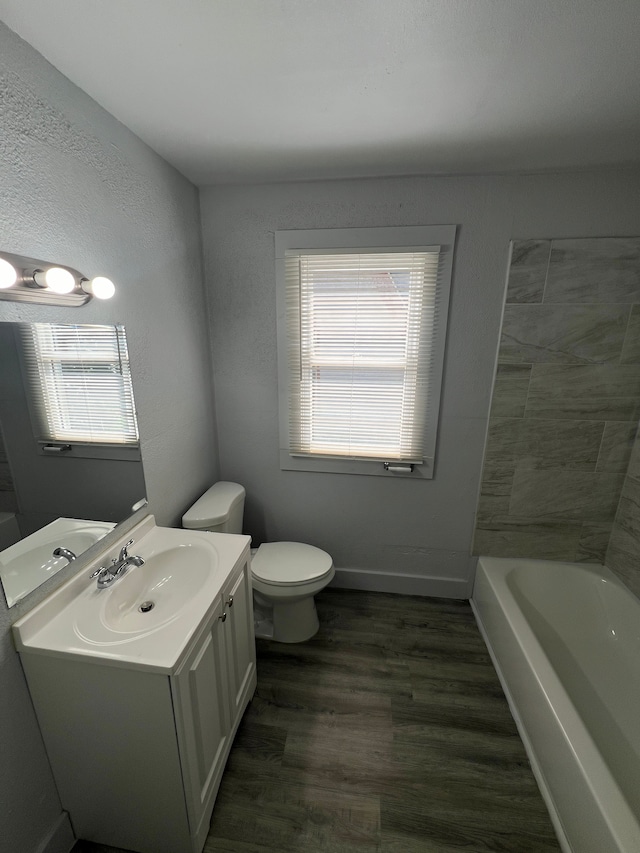 bathroom with a wealth of natural light, toilet, vanity, and hardwood / wood-style flooring