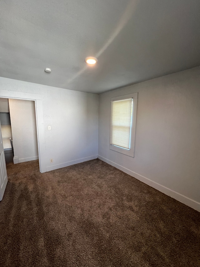 spare room with dark carpet