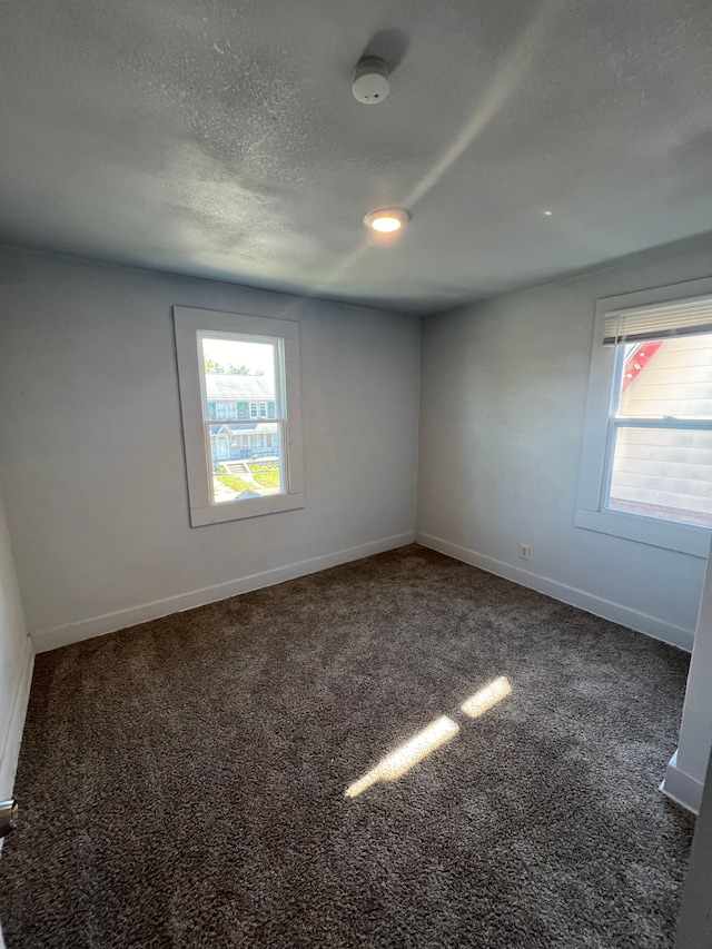 carpeted empty room with a textured ceiling