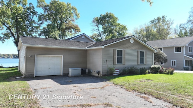 view of front of house featuring a front yard, a garage, driveway, and a shingled roof