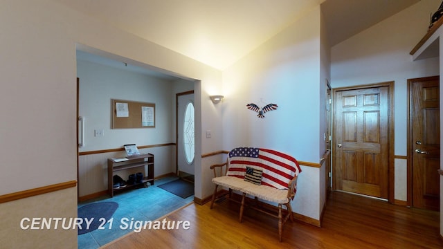 foyer featuring lofted ceiling, wood finished floors, and baseboards