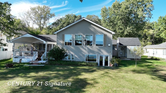 rear view of property with a wooden deck, fence, a lawn, and an outdoor fire pit