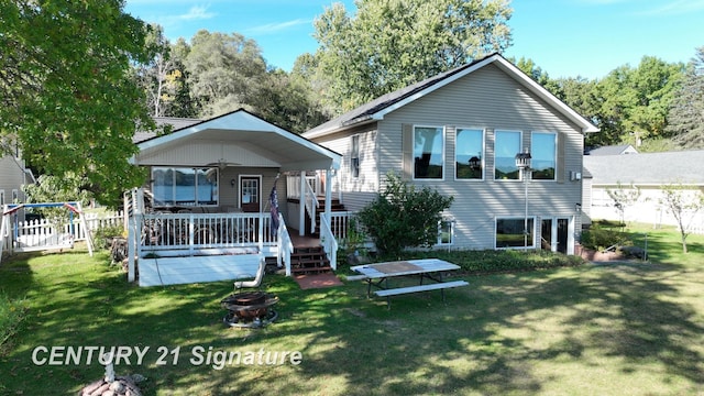 view of front facade featuring a wooden deck, an outdoor fire pit, a front yard, and fence