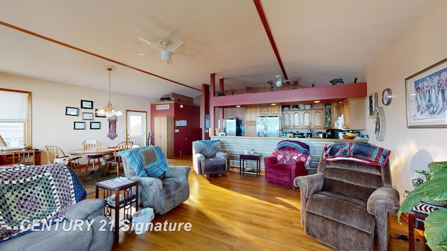 living area featuring light wood finished floors, ceiling fan with notable chandelier, and lofted ceiling