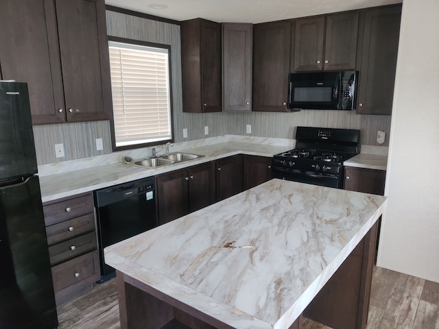 kitchen featuring sink, dark brown cabinets, a kitchen island, black appliances, and hardwood / wood-style flooring