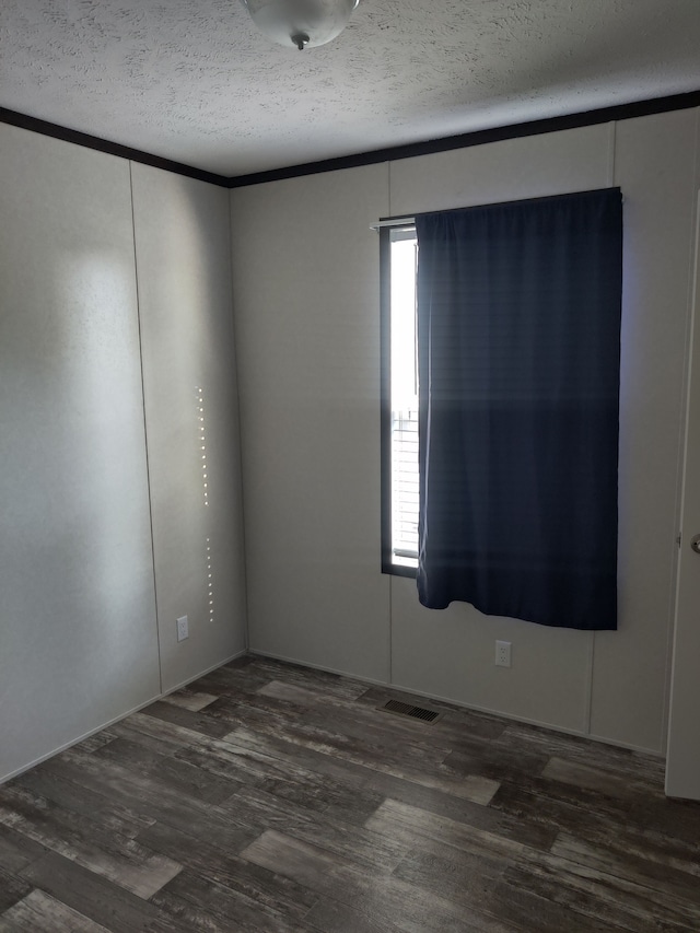 empty room with a textured ceiling and dark hardwood / wood-style floors