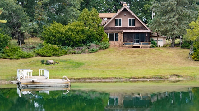 back of property with a lawn, a deck with water view, and a sunroom