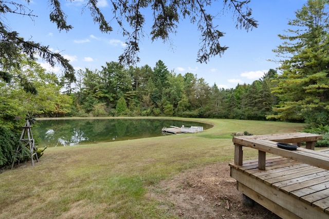 view of community with a dock, a lawn, and a water view