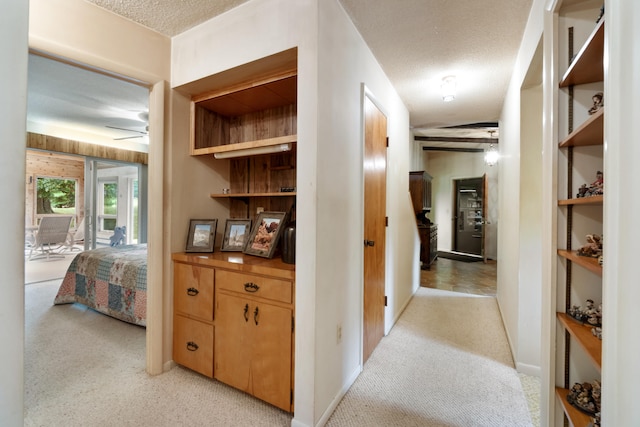 hall with a textured ceiling and light carpet