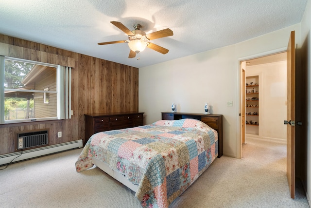 bedroom with ceiling fan, light colored carpet, a baseboard heating unit, and wood walls