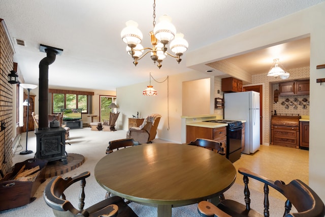 dining space featuring a notable chandelier, a wood stove, and a textured ceiling