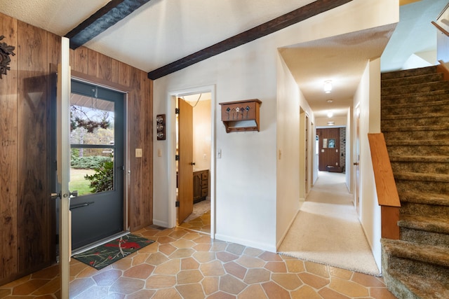 foyer with wooden walls and beamed ceiling