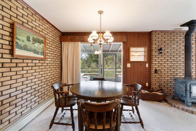 carpeted dining space featuring wooden walls, a wood stove, a textured ceiling, brick wall, and a chandelier