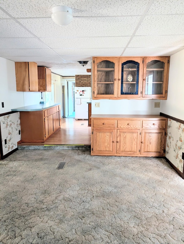 kitchen with a paneled ceiling, white fridge, and light carpet