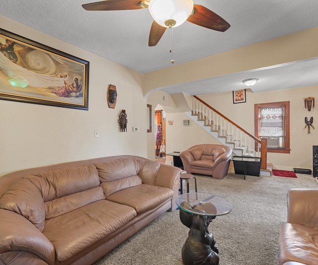 living room featuring carpet flooring, ceiling fan, and a textured ceiling