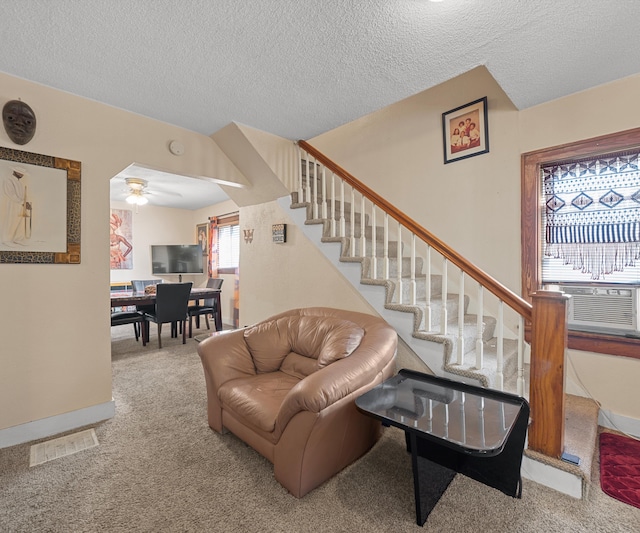 carpeted living room featuring a textured ceiling, cooling unit, and ceiling fan