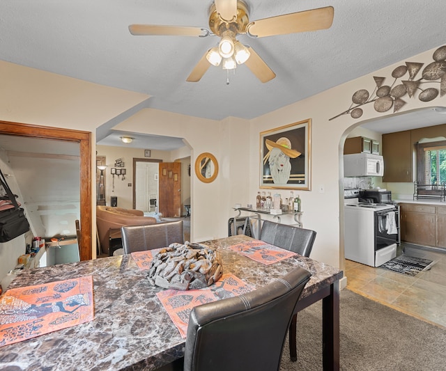 carpeted dining area featuring a textured ceiling and ceiling fan