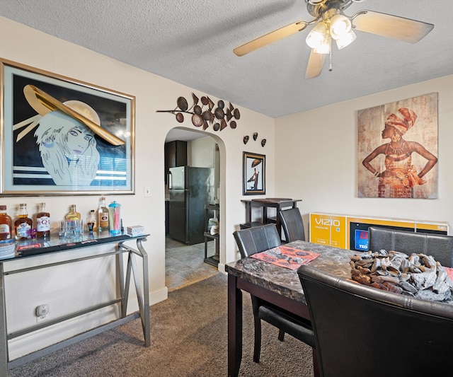 carpeted dining space with a textured ceiling and ceiling fan