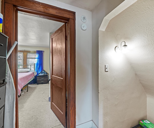 hallway with a textured ceiling, carpet floors, and lofted ceiling