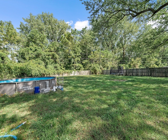 view of yard with a trampoline and a fenced in pool