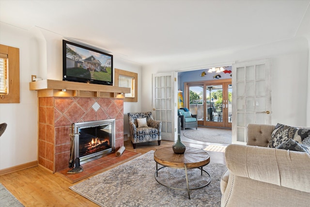 living room with hardwood / wood-style floors, a tiled fireplace, and french doors