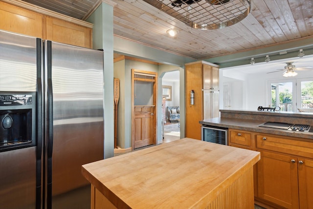 kitchen featuring track lighting, wooden counters, ornamental molding, stainless steel appliances, and beverage cooler