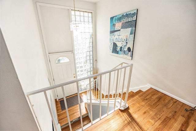 stairs featuring hardwood / wood-style flooring and a chandelier