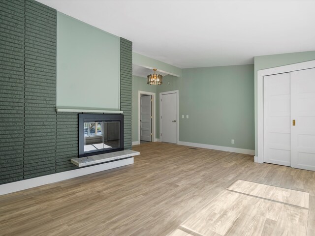 unfurnished living room with a notable chandelier and light wood-type flooring